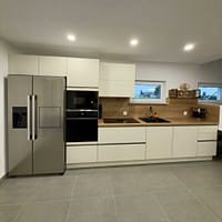 Elegant modern kitchen featuring white cabinets, a wooden backsplash, and stainless steel appliances.