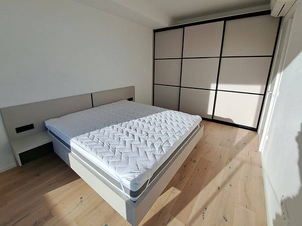 Contemporary bedroom with custom-built wardrobe and clean, minimalist decor.