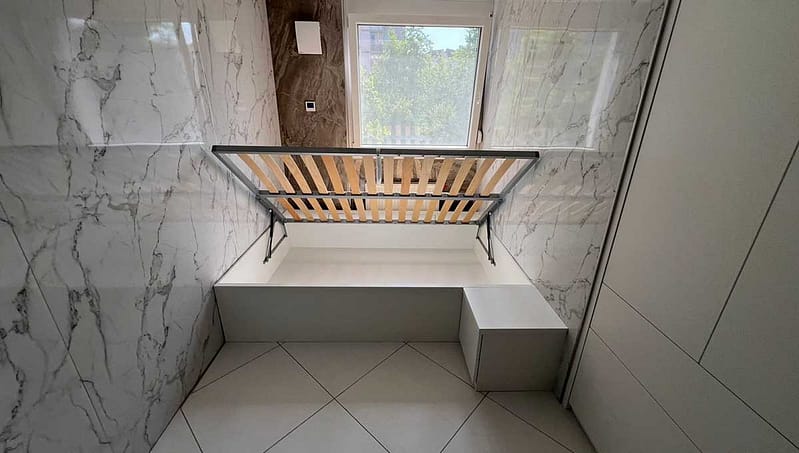 Foldable bed frame in a modern bedroom with marble walls and large window.