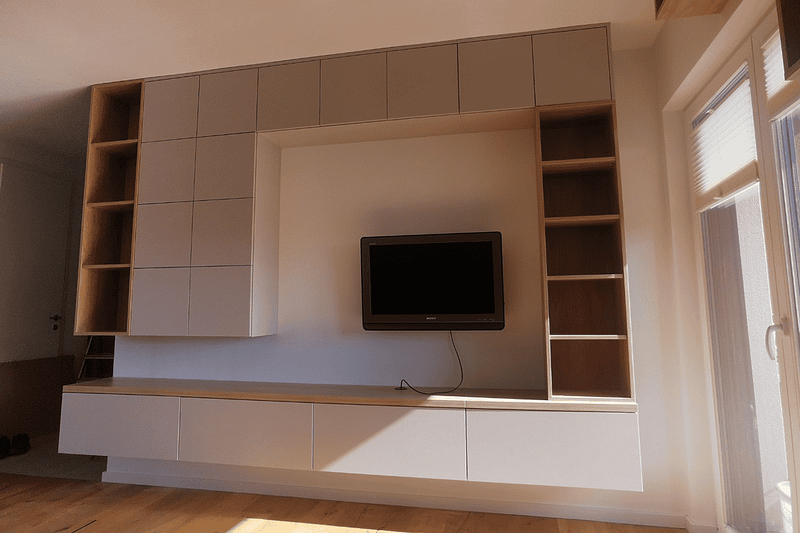 Custom-made TV wall unit with storage and shelves in a living room.