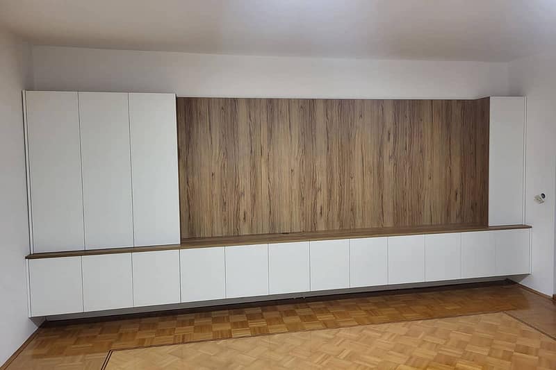 Modern living room storage unit with white cabinets and wooden accents for a sleek look.