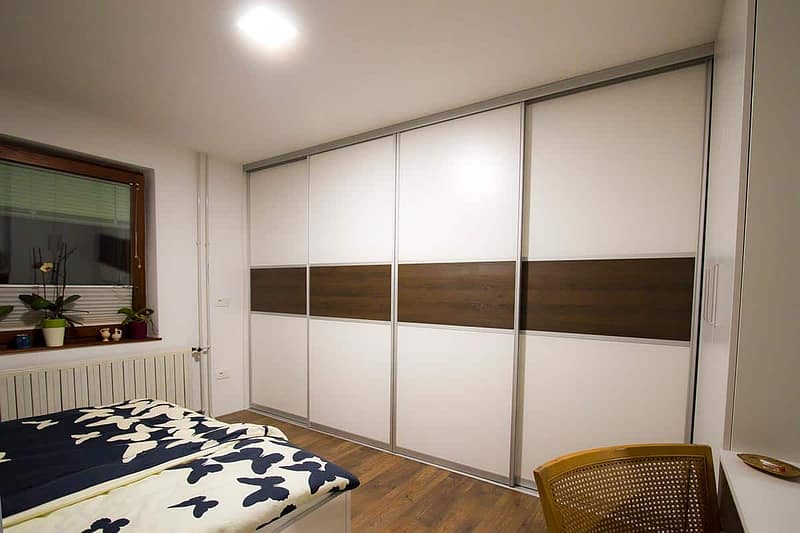 Custom built-in wardrobe with sliding doors in a contemporary bedroom setting.