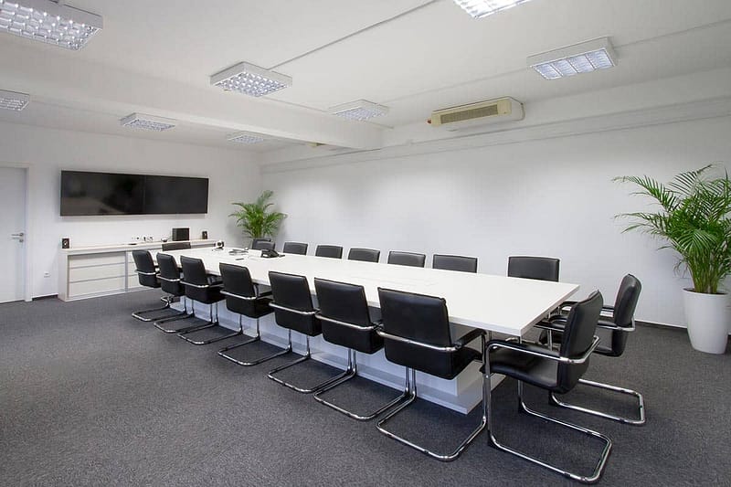 Spacious conference room with modern furniture and presentation screen.