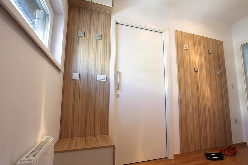 Wooden hallway wall with hooks and seating, custom furniture design.