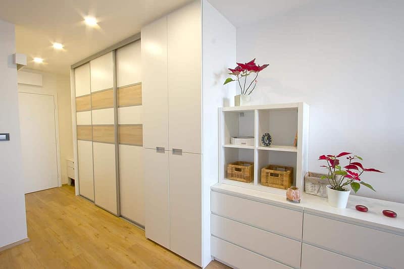 Stylish white and wood-finished wardrobe with sliding doors in a contemporary hallway.