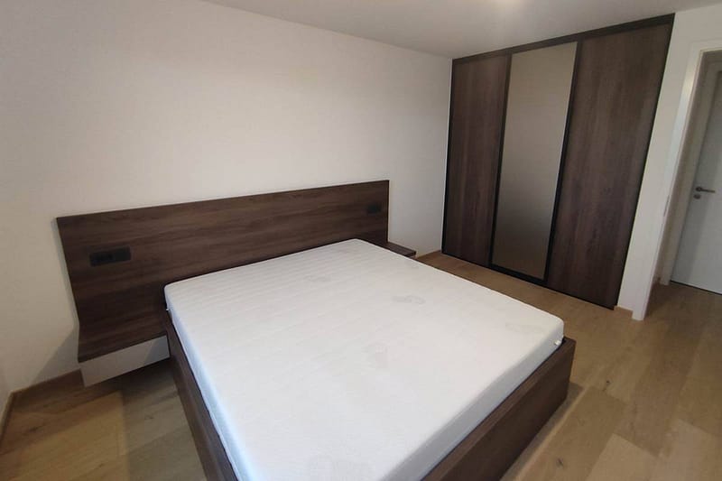 Modern bedroom with custom wooden bed and wardrobe in minimalist design.