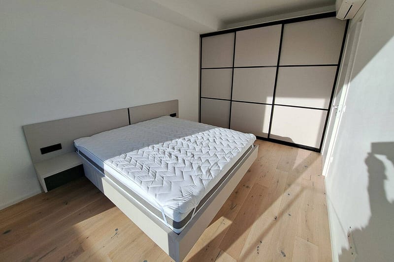 Contemporary bedroom with custom-built wardrobe and clean, minimalist decor.