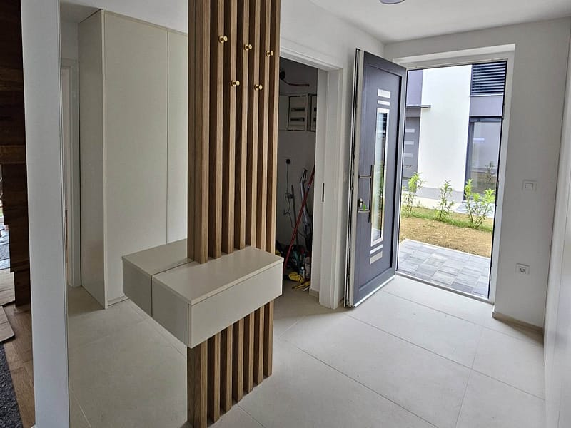 Custom entryway furniture with wooden slats and storage bench in a contemporary home.